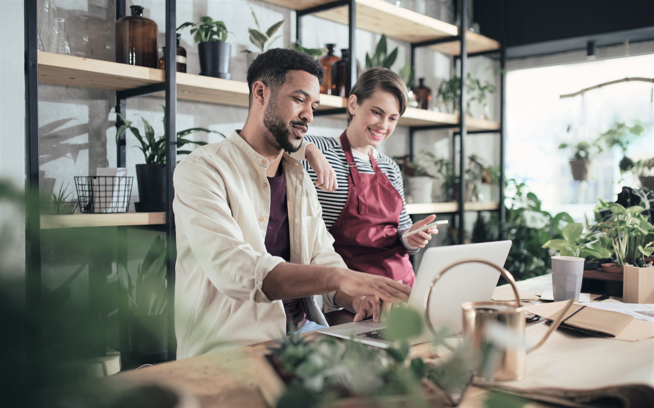 Shop assistants with laptop working in potted plant store, small business concept.